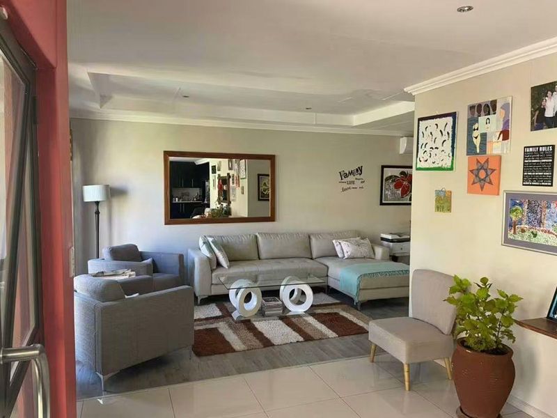 A well-maintained living room featuring tiled flooring, a recessed ceiling, and direct access to an outdoor area via a sliding door.