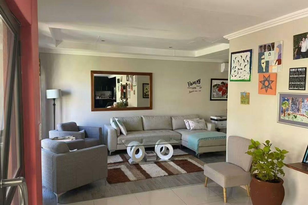 A well-maintained living room featuring tiled flooring, a recessed ceiling, and direct access to an outdoor area via a sliding door.