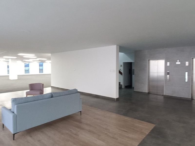 Spacious modern office lobby area featuring dual elevators, recessed lighting, and a combination of tiled and laminate flooring finishes.
