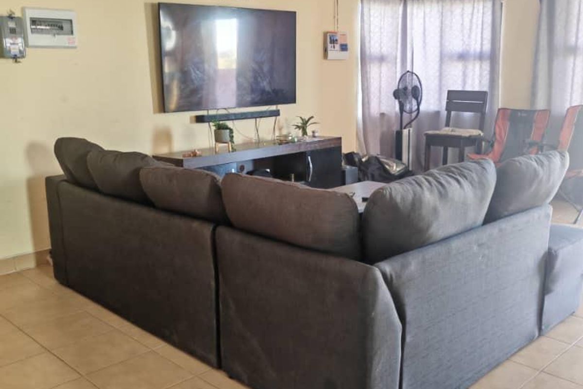 A living room featuring ceramic floor tiles, neutral wall paint, and a wall-mounted television setup.