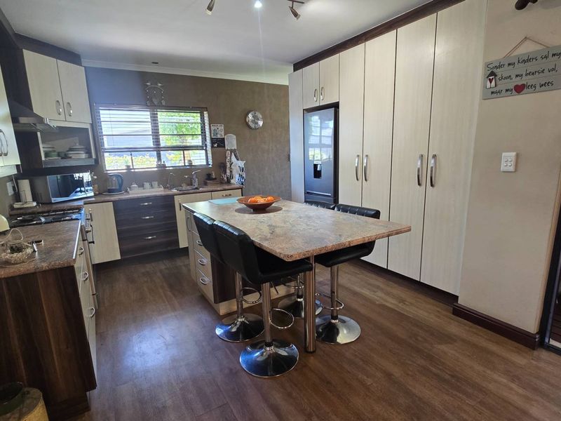 A well-maintained kitchen featuring modern cabinetry, a central island with seating, stone countertops, and integrated appliances, offering a functional and contemporary cooking space.