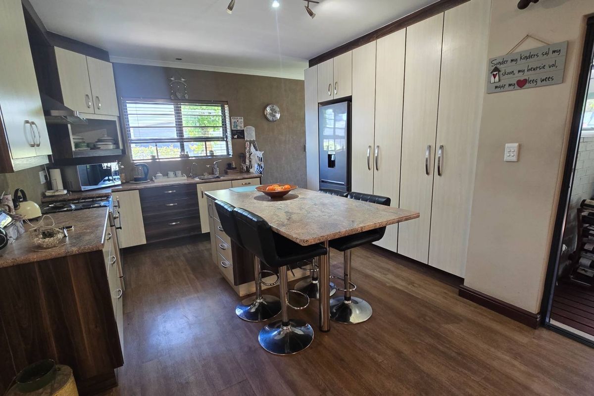A well-maintained kitchen featuring modern cabinetry, a central island with seating, stone countertops, and integrated appliances, offering a functional and contemporary cooking space.