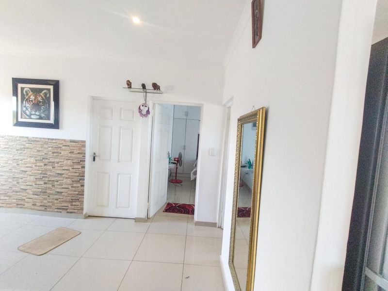 A bright hallway featuring tiled flooring, stone-look wall accents, and access to adjacent rooms through panelled doors.