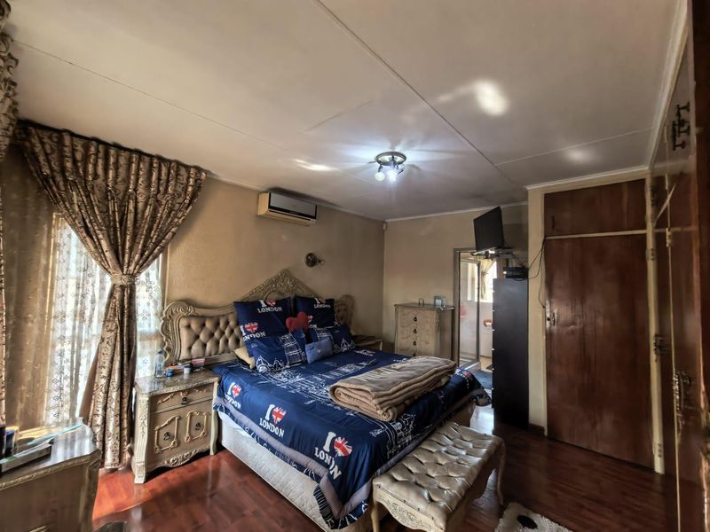 A bedroom featuring laminate flooring, a built-in cupboard, and an installed air conditioning unit.