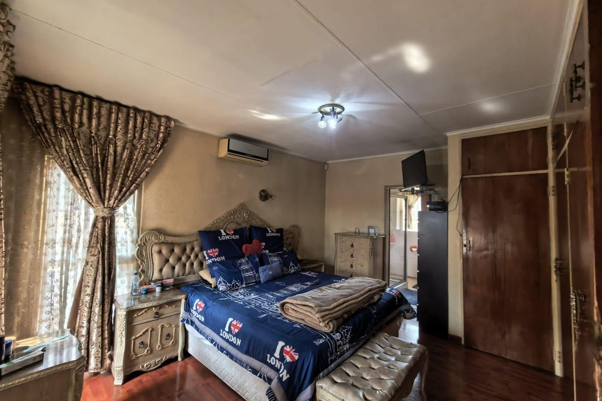A bedroom featuring laminate flooring, a built-in cupboard, and an installed air conditioning unit.