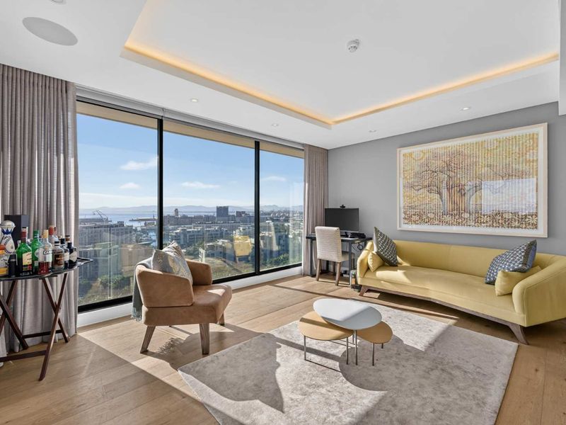 Modern living room featuring floor-to-ceiling windows with expansive city and harbour views, recessed cove lighting, and high-quality timber flooring.
