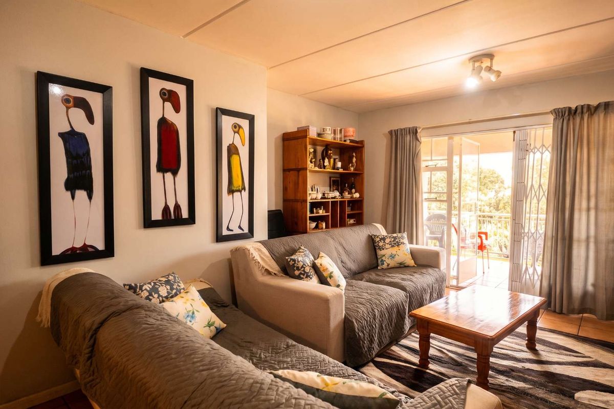 A comfortable living room featuring tiled flooring and a sliding glass door that opens onto a balcony, providing natural light and outdoor access.