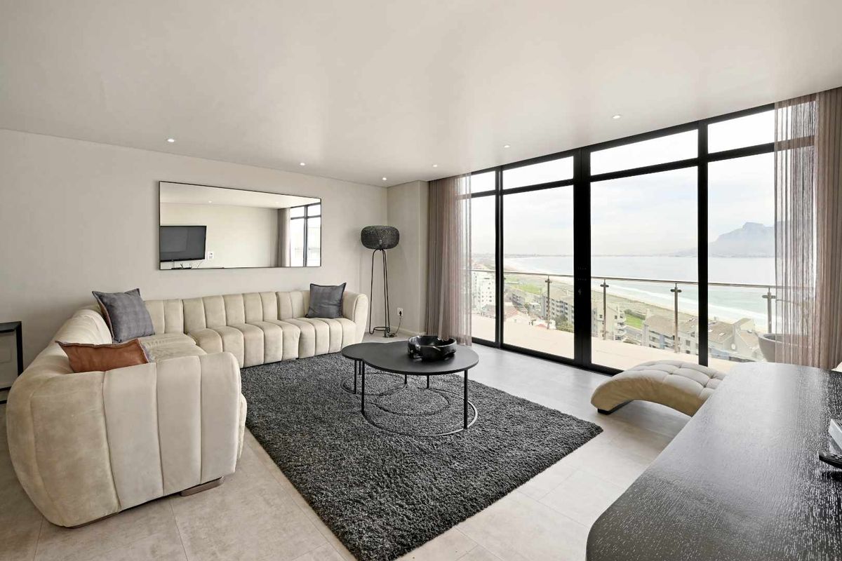 Spacious living area featuring floor-to-ceiling windows with panoramic coastal views and access to a private balcony.