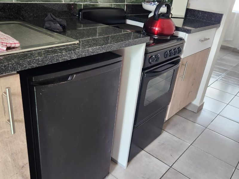 A functional kitchen featuring granite countertops, a green subway tile backsplash, and modern cabinetry with ceramic floor tiles.