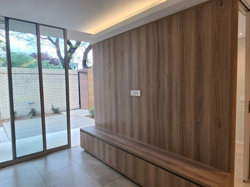 Modern living area featuring a wood veneer feature wall, built-in cabinetry, and large sliding glass doors opening to an outdoor patio space.