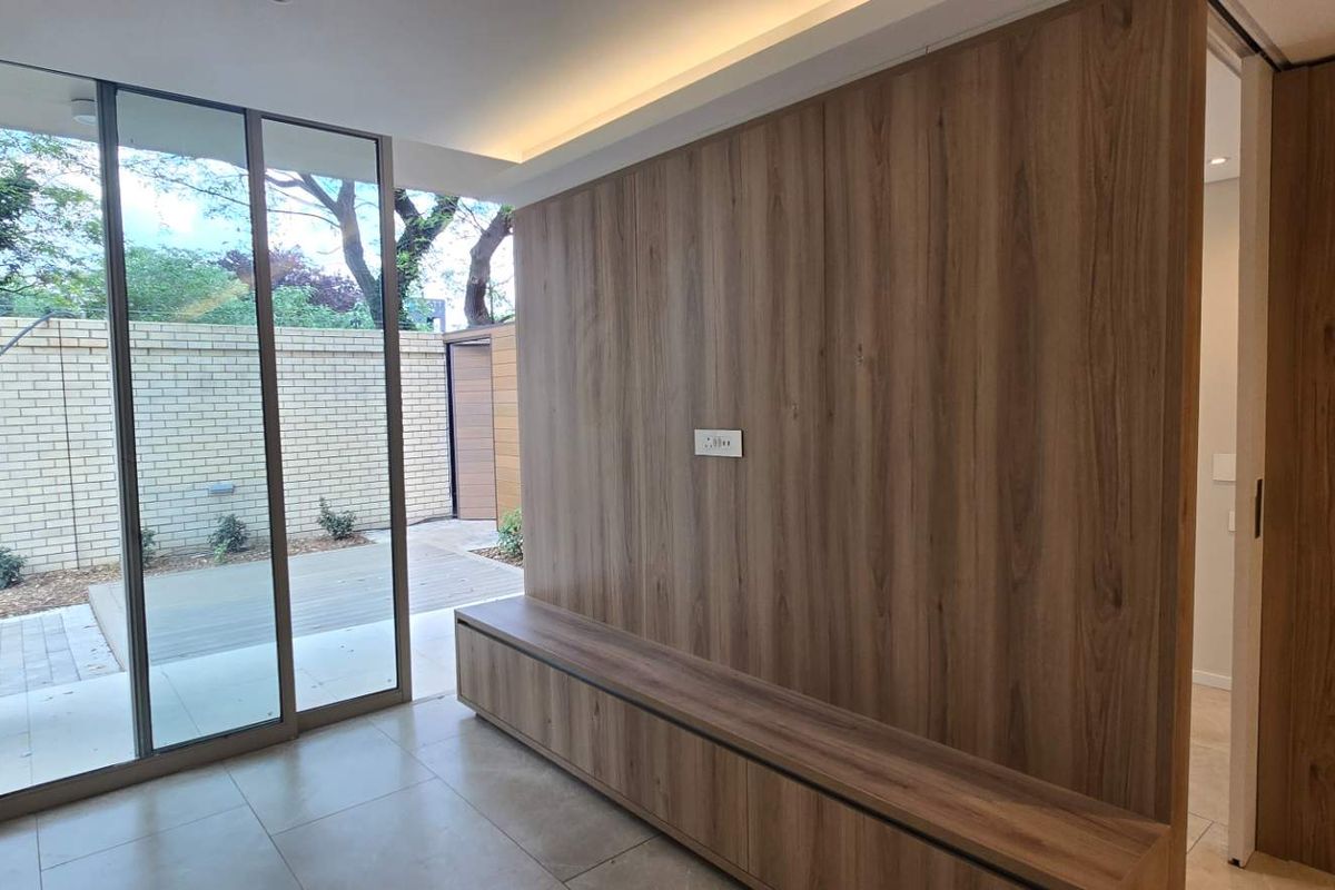 Modern living area featuring a wood veneer feature wall, built-in cabinetry, and large sliding glass doors opening to an outdoor patio space.
