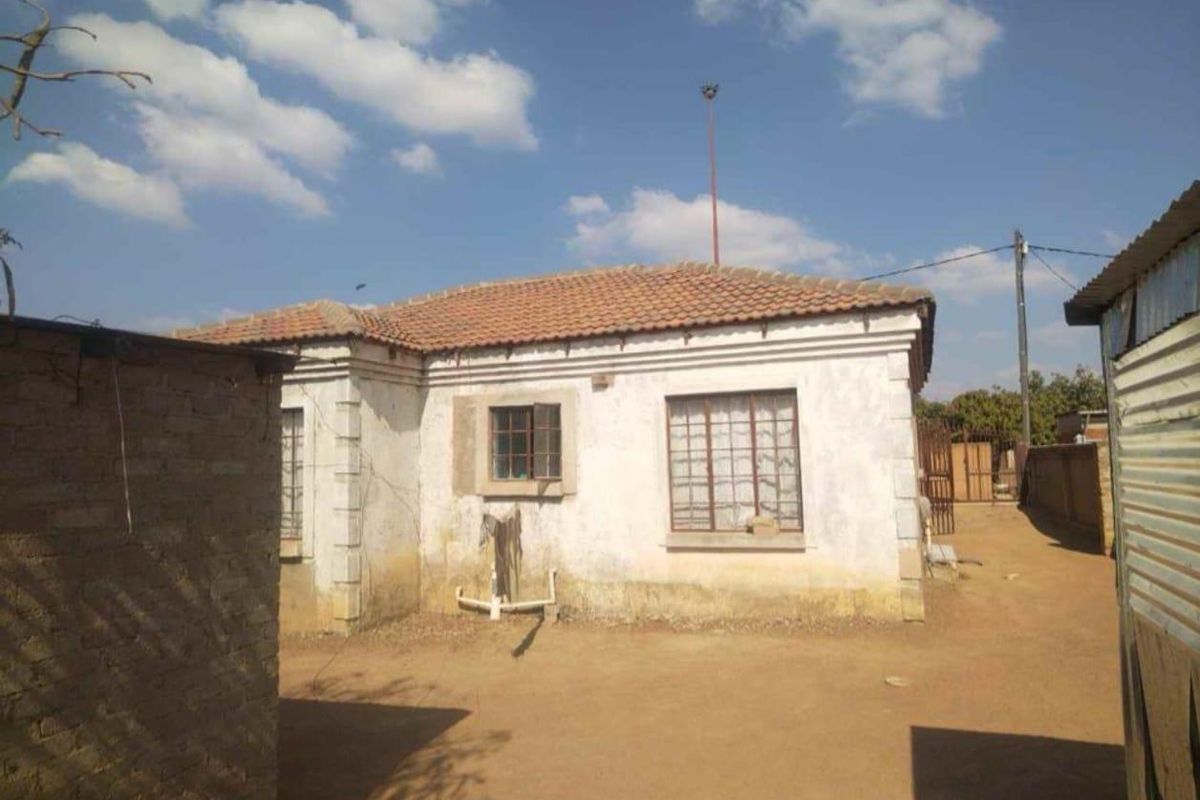 Rear view of a single-story residential property featuring a terracotta tiled roof and plastered exterior walls with metal security-barred windows.