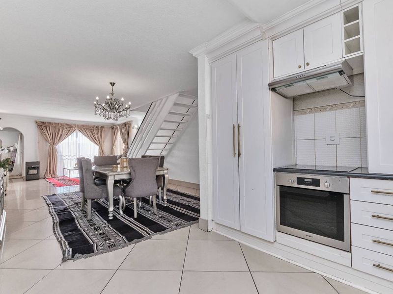 Open-plan living and dining area featuring a modern kitchen with built-in oven, extractor fan, and tiled flooring throughout.