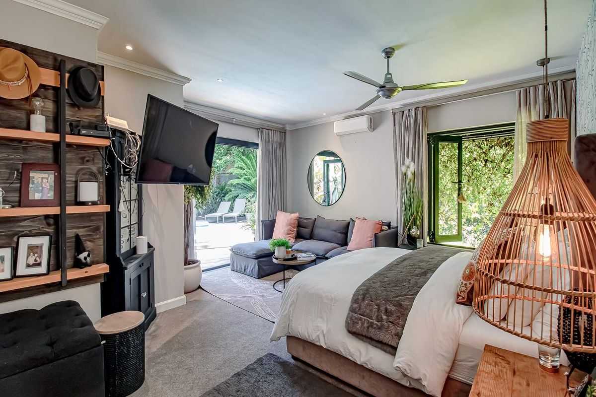 Spacious bedroom featuring a ceiling fan, wall-mounted air conditioning unit, and large sliding doors providing direct access to the outdoor patio area.