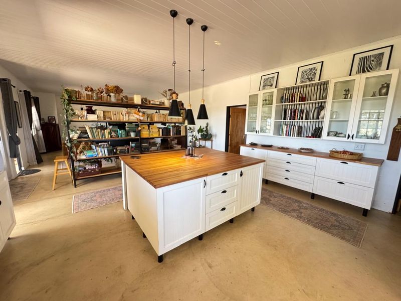 Spacious kitchen featuring a large central island with a timber countertop, extensive built-in cabinetry, and elegant pendant lighting in a bright, open-plan setting.