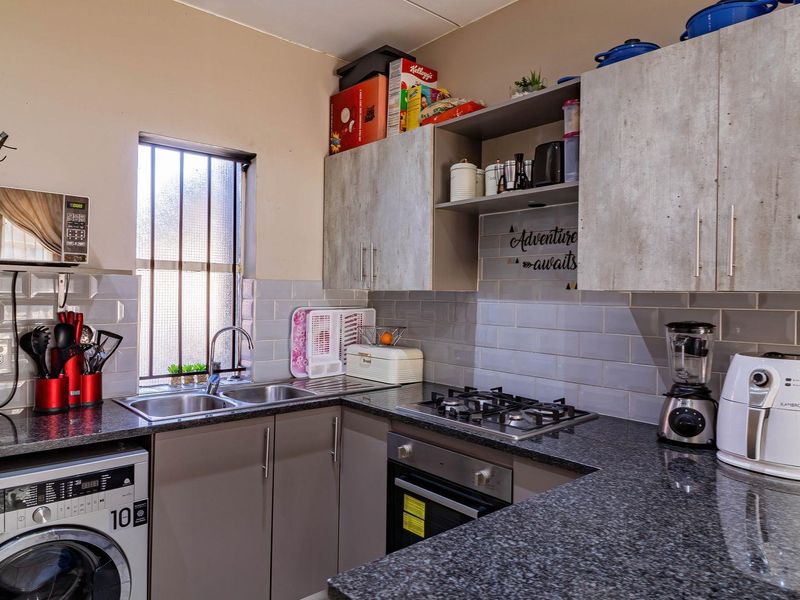 A functional kitchen featuring granite countertops, subway tile backsplash, built-in cabinetry, a gas hob, and an integrated oven with space for laundry appliances.