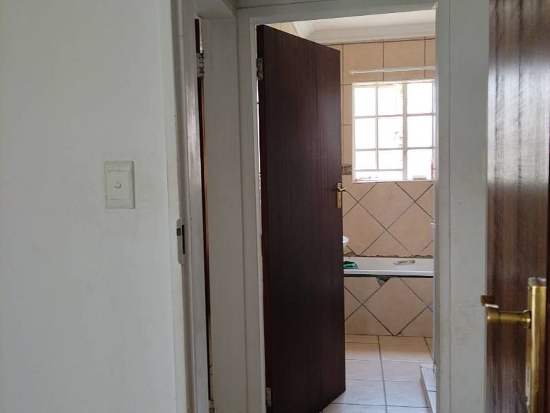 A view through a hallway leading into a bathroom featuring tiled flooring and standard internal doors.