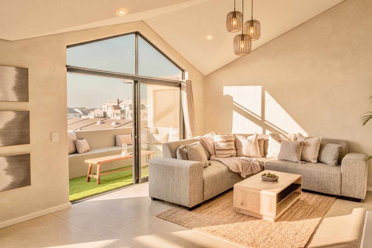 Bright and airy living room featuring high vaulted ceilings, large sliding glass doors, and seamless access to a private balcony with artificial turf.