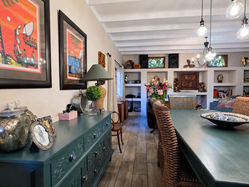 A cozy living area featuring exposed beam ceilings, built-in wall shelving, and stylish pendant lighting, creating a warm and inviting atmosphere.