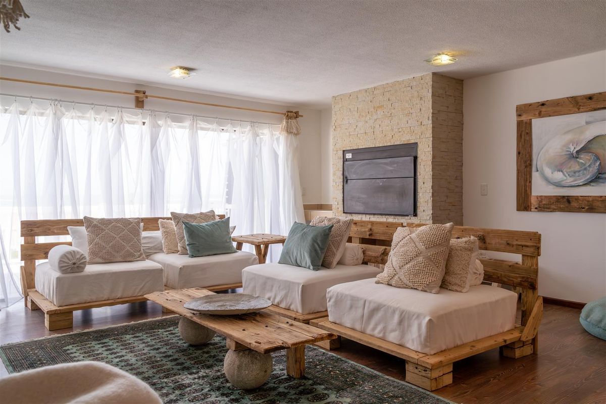 A cozy living room featuring a stone-clad fireplace and large windows that allow for ample natural light.