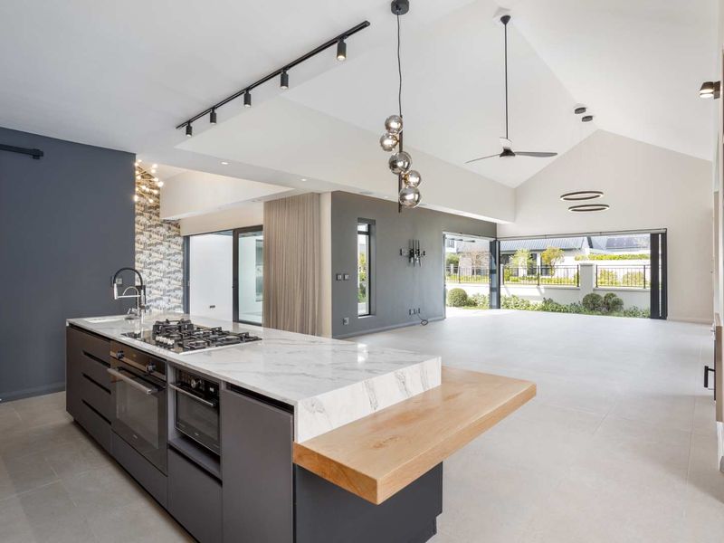 Spacious open-plan living area featuring a modern kitchen island with marble countertops, high-end built-in appliances, and seamless flow to the outdoor patio.
