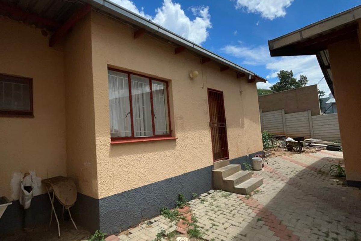 Rear exterior view of the property featuring paved courtyard area, concrete steps, and access to the building structure.