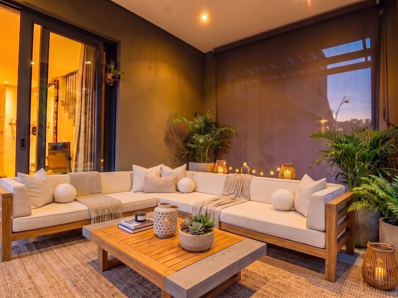 A well-maintained covered patio featuring sliding glass doors, recessed lighting, and an outdoor roller blind, creating a cozy and inviting outdoor living space.