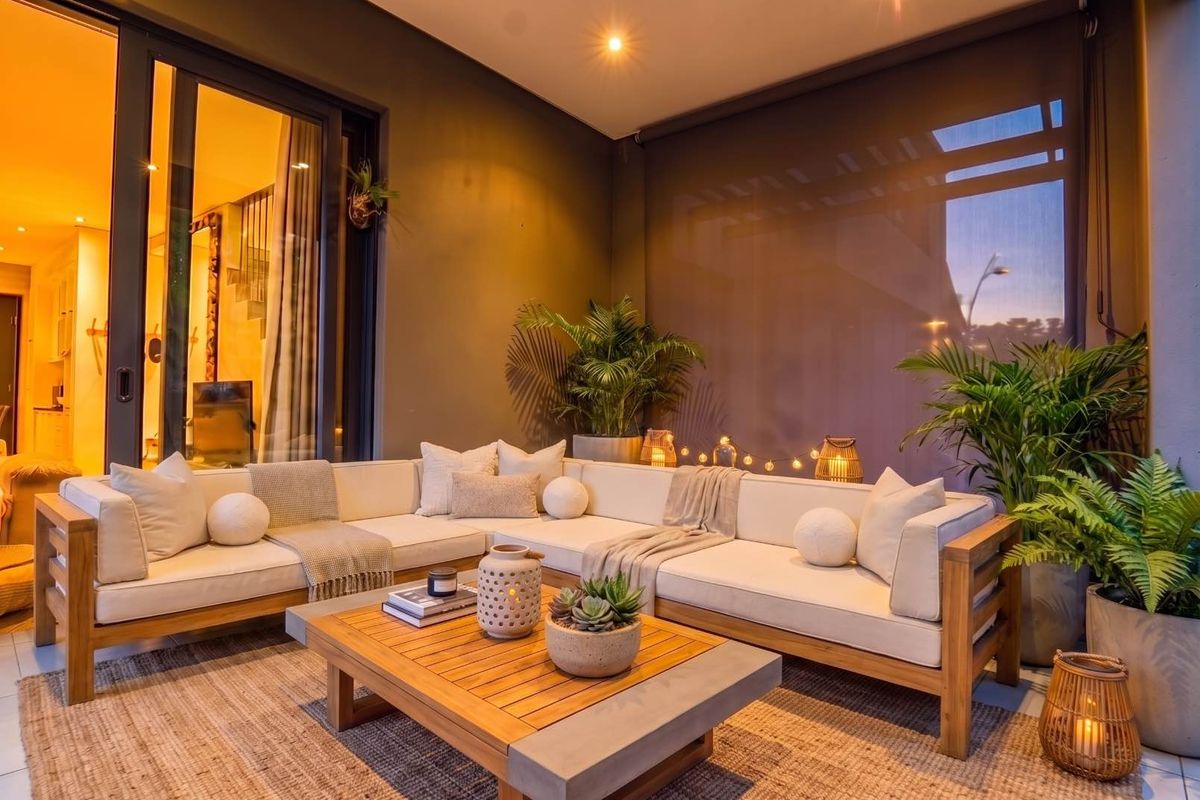 A well-maintained covered patio featuring sliding glass doors, recessed lighting, and an outdoor roller blind, creating a cozy and inviting outdoor living space.