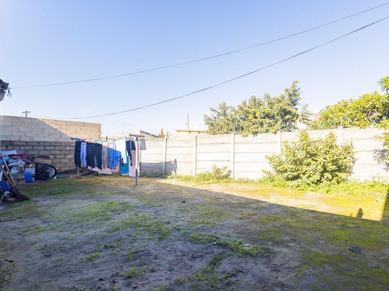 A rear yard area featuring a precast concrete boundary wall with security razor wire, offering a blank canvas for landscaping or outdoor development.