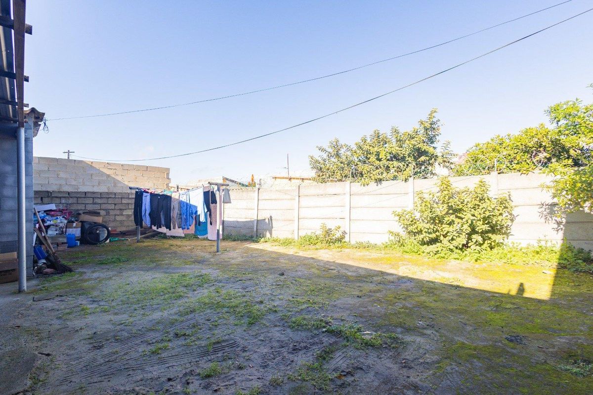 A rear yard area featuring a precast concrete boundary wall with security razor wire, offering a blank canvas for landscaping or outdoor development.