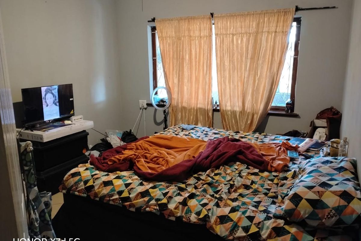 A bedroom featuring a window with security bars and curtain fixtures, providing natural light to the space.