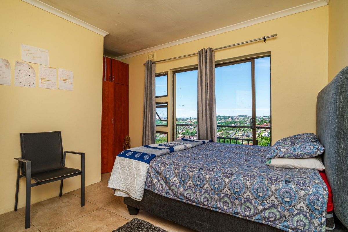 A bedroom featuring built-in wooden cabinetry, tiled flooring, and large sliding glass doors that open to a balcony with expansive city views.