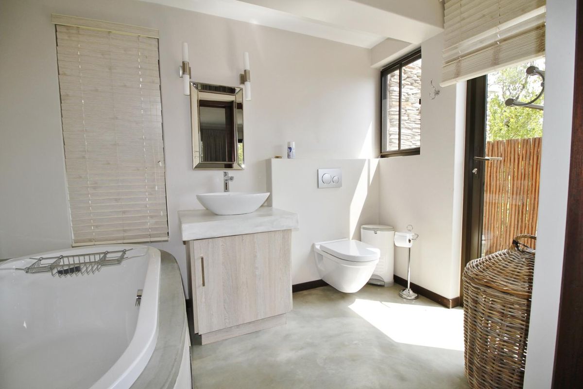 Modern bathroom featuring a vessel sink vanity, wall-mounted toilet, and a built-in bathtub with polished concrete finishes and natural light.