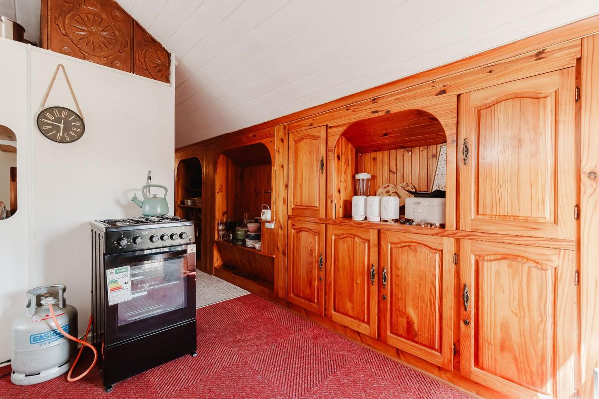 A kitchen area featuring extensive built-in wooden cabinetry, a gas stove with oven, and a vaulted tongue and groove ceiling.
