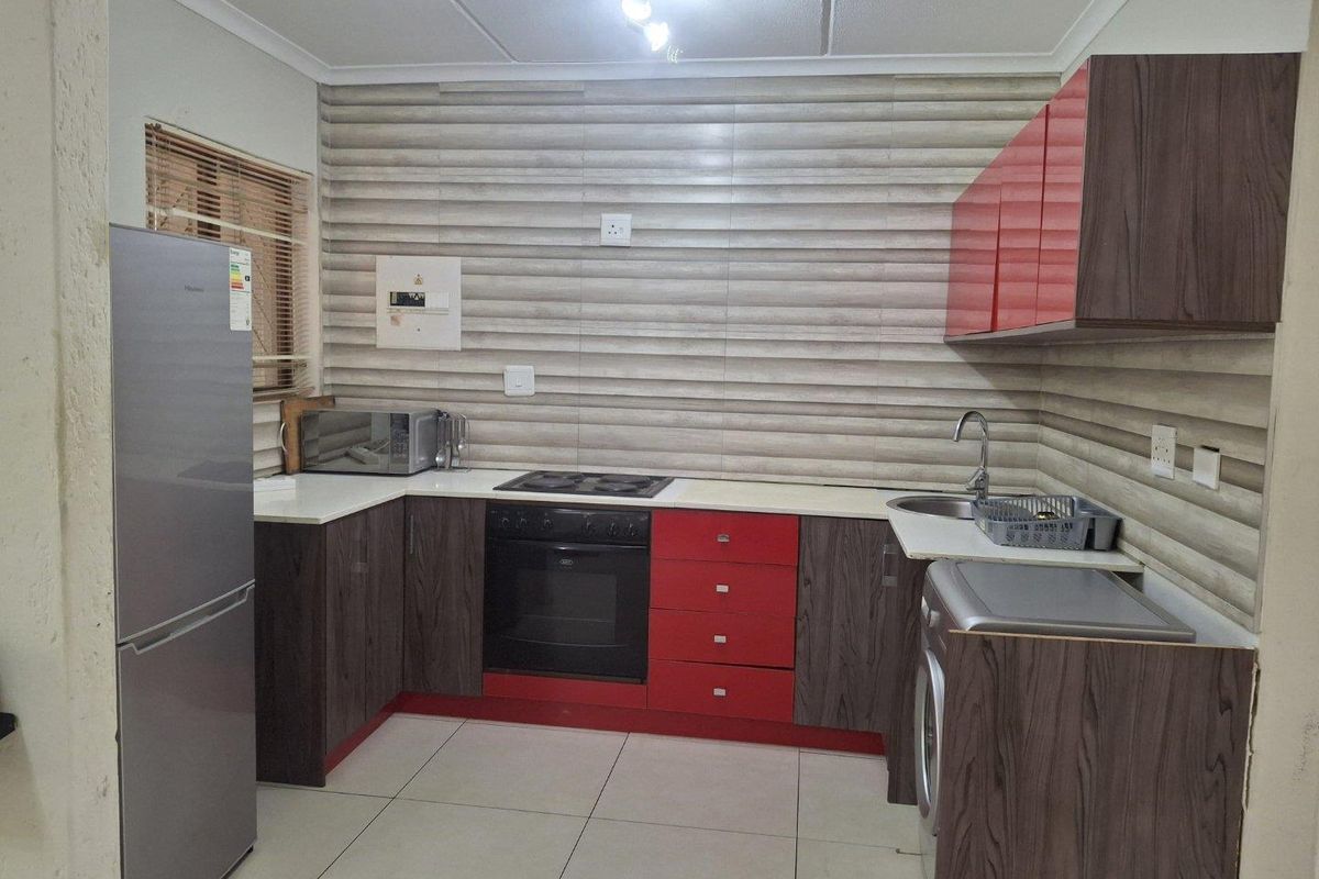 A functional kitchen featuring modern two-tone cabinetry, built-in oven and hob, tiled backsplash, and tiled flooring, providing a practical workspace for daily cooking.