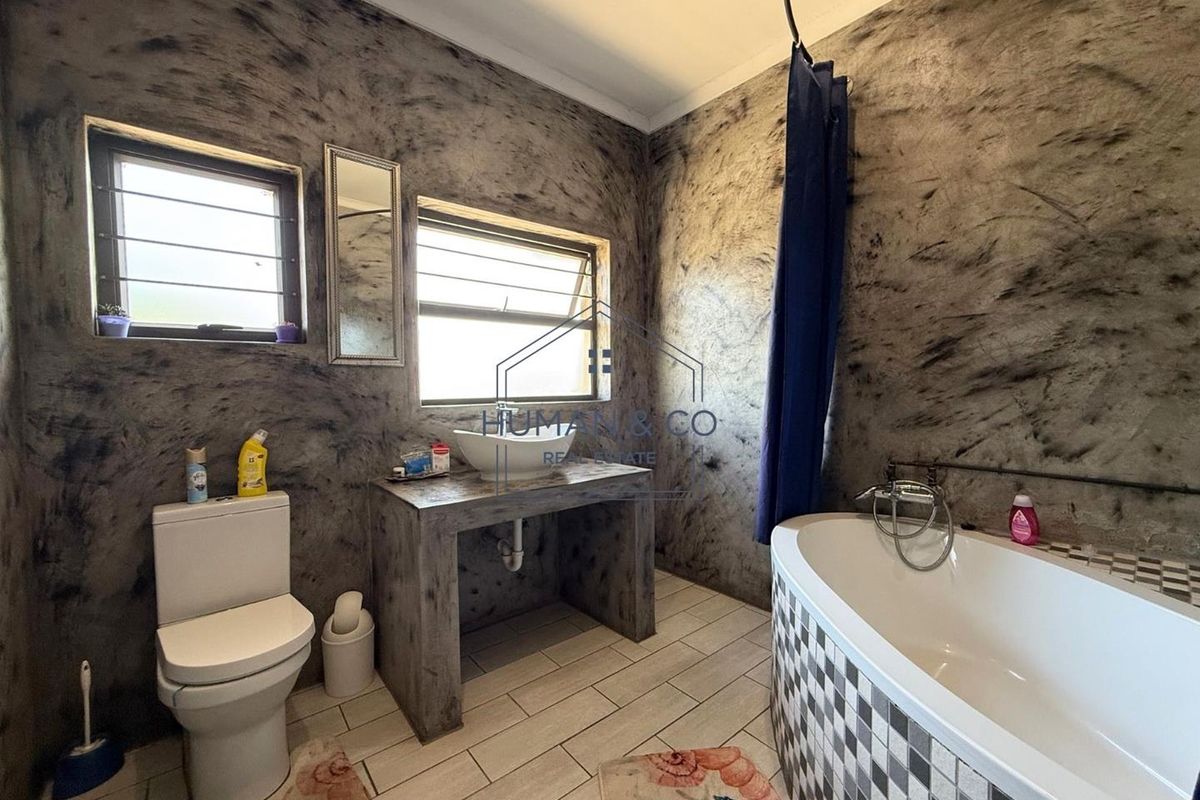 Bathroom featuring a vessel sink on a concrete vanity, a bathtub with a tiled surround, and distinctive textured wall finishes.