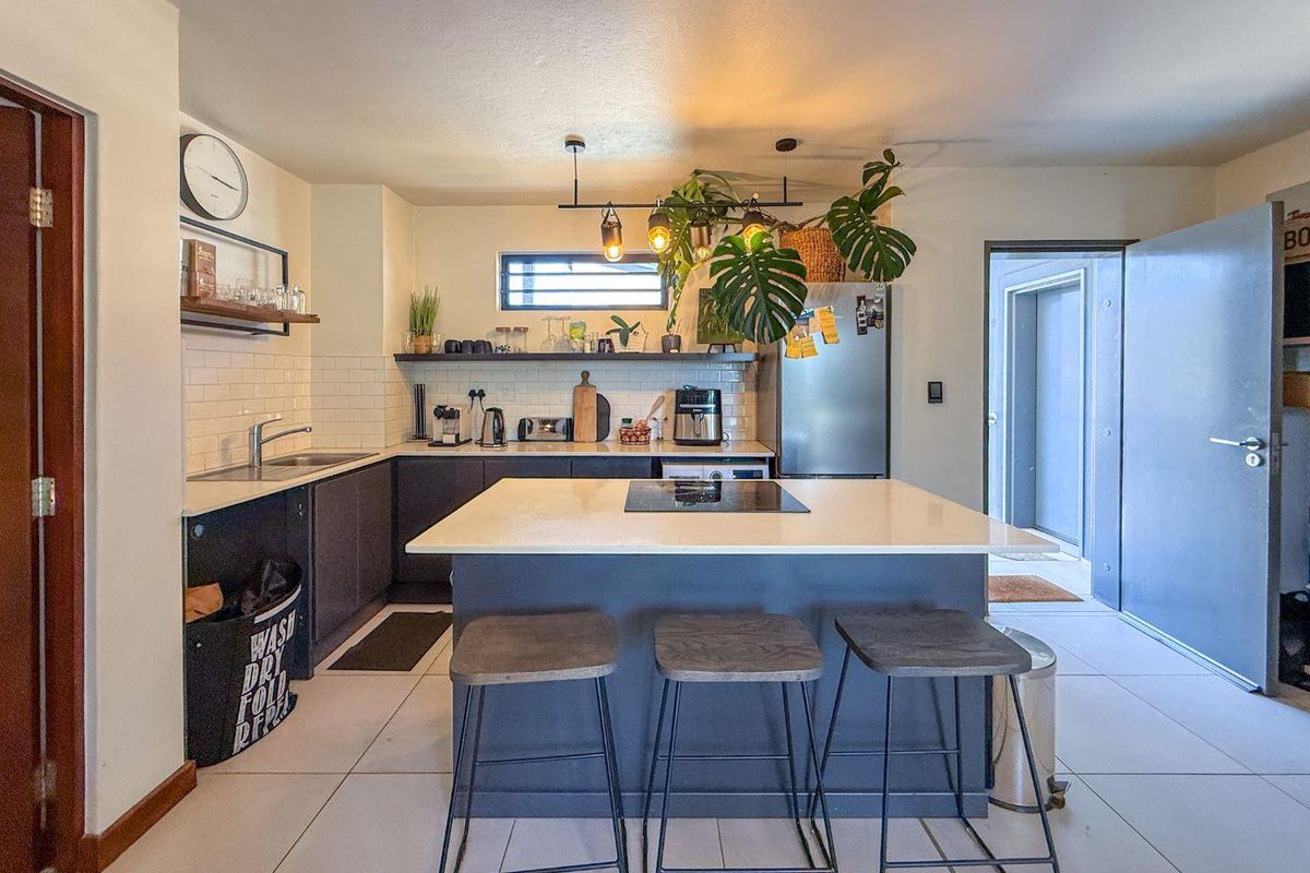 Modern kitchen featuring a central island with a built-in cooktop, subway tile backsplash, sleek cabinetry, and contemporary pendant lighting.