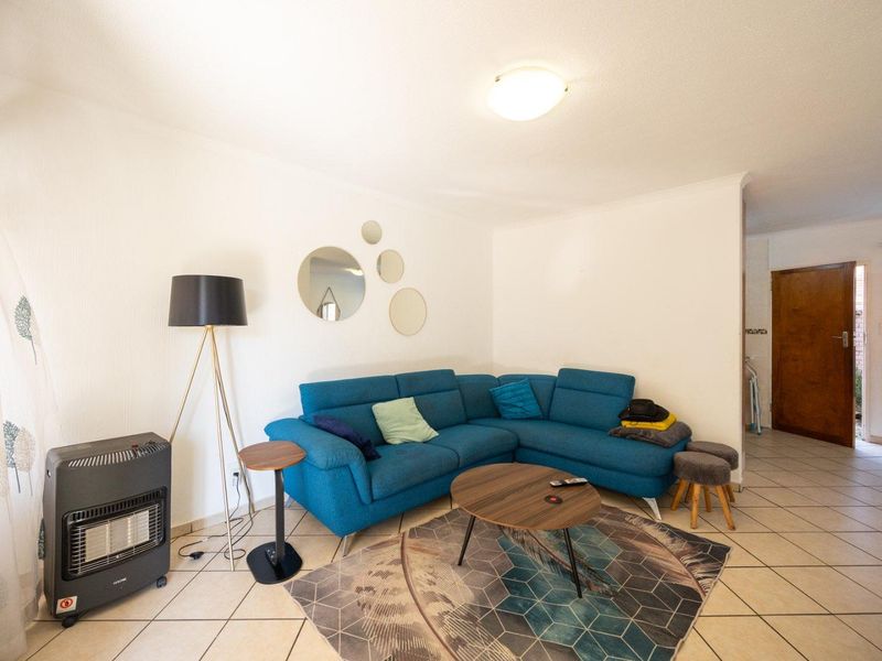 A living room area featuring neutral tiled flooring and a coved ceiling, providing a functional and well-lit space.