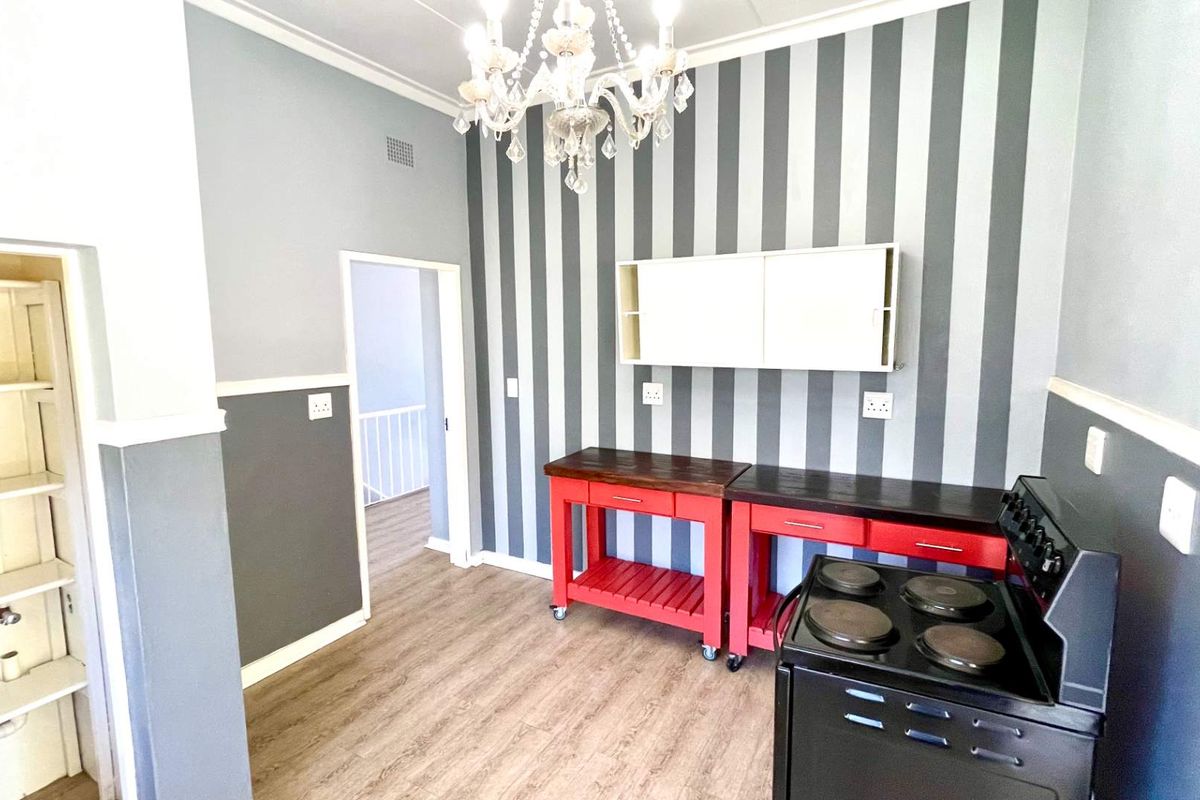 Kitchen area featuring wood-look flooring, striped accent wall, built-in wall cabinetry, and a freestanding electric stove.