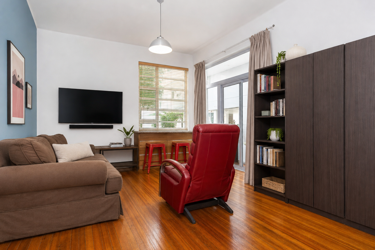 A well-maintained living room featuring polished hardwood flooring, built-in storage cabinetry, and a sliding glass door providing access to an outdoor area.