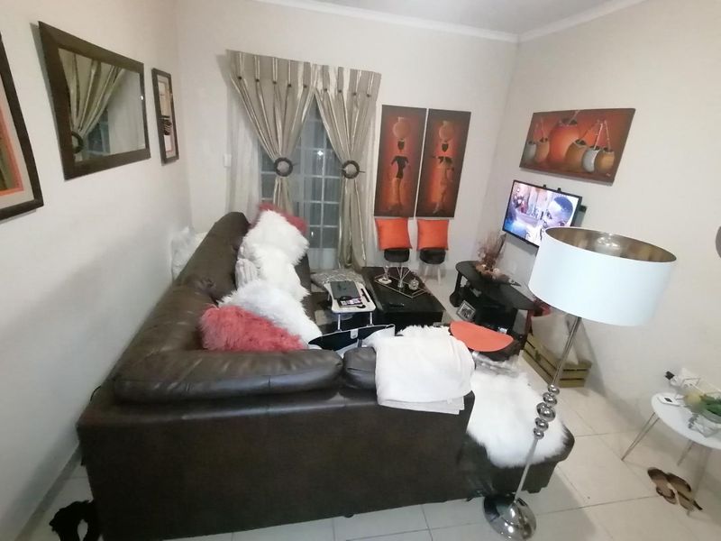 A compact living room featuring tiled flooring and a sliding glass door providing access to the exterior.