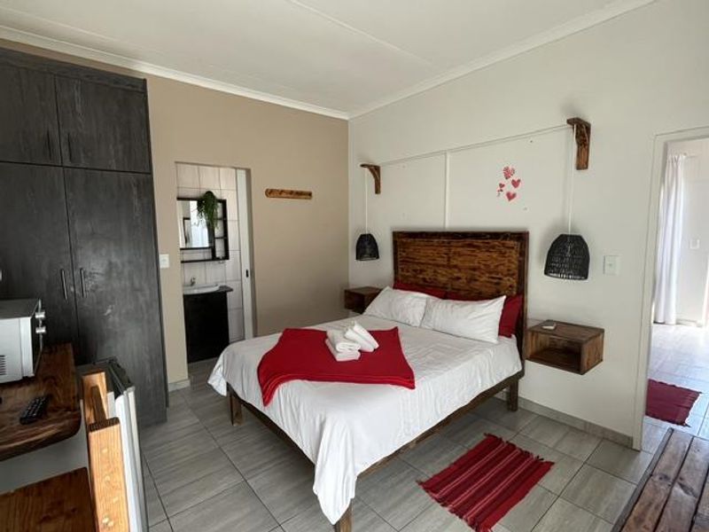 A well-maintained bedroom featuring built-in cupboards, tiled flooring, and an adjoining en-suite bathroom with modern finishes.