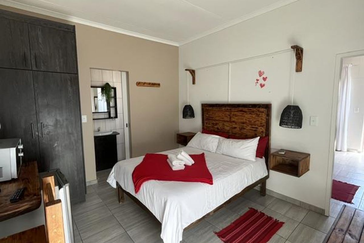 A well-maintained bedroom featuring built-in cupboards, tiled flooring, and an adjoining en-suite bathroom with modern finishes.