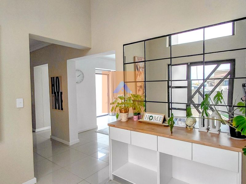 A bright and spacious hallway featuring high ceilings, neutral wall finishes, and tiled flooring, leading into the main living areas of the home.