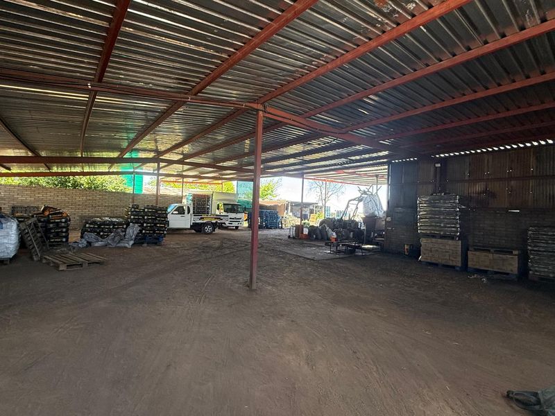 Large open-sided utility shed with corrugated metal roofing and steel support structure, suitable for agricultural storage or farm operations.