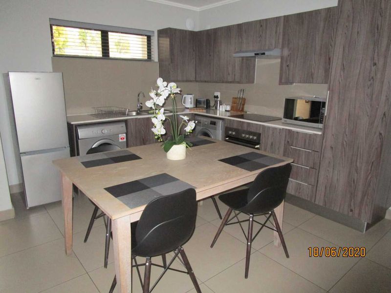 Modern kitchen featuring wood-grain cabinetry, integrated appliances, tiled flooring, and a functional layout with ample storage space.