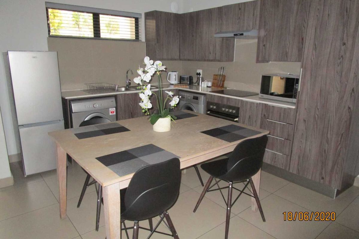 Modern kitchen featuring wood-grain cabinetry, integrated appliances, tiled flooring, and a functional layout with ample storage space.