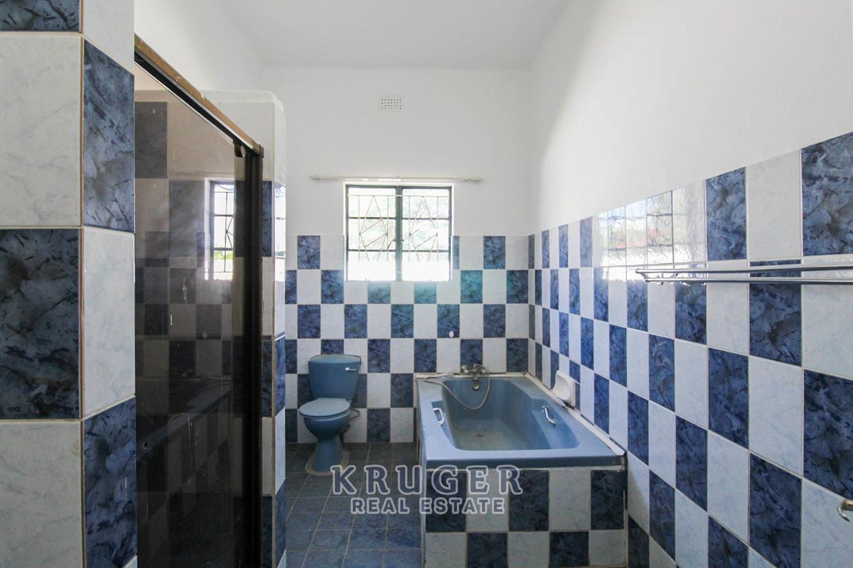 A dated bathroom featuring blue and white checkered wall tiles, a built-in bathtub, a separate shower enclosure, and a blue toilet.