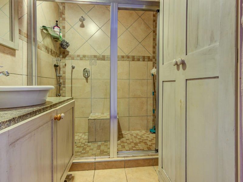 A functional bathroom featuring a vanity with a granite countertop, vessel sink, and a tiled shower enclosure with a built-in seat.