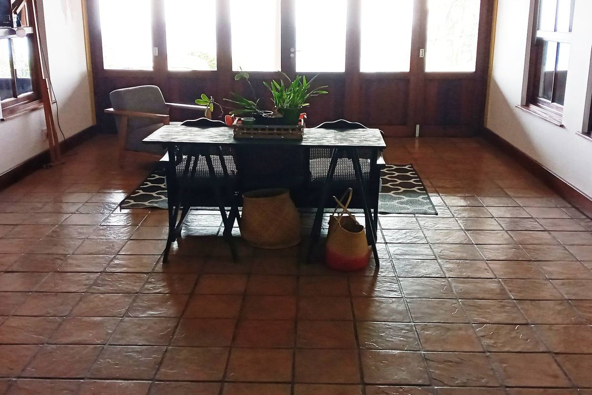 Spacious living area featuring terracotta floor tiles and large timber-framed glass doors providing ample natural light and access to the exterior.